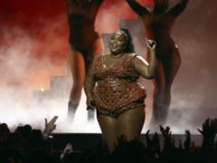 Puffy Lizzo in a black shirt barely covered her bare chest