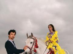 Barefoot Yekaterina Kukhar in a bright embroidery saddled a horse in the field