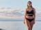 A plump model plus-size Ashley Graham in a bikini posed against the ocean
